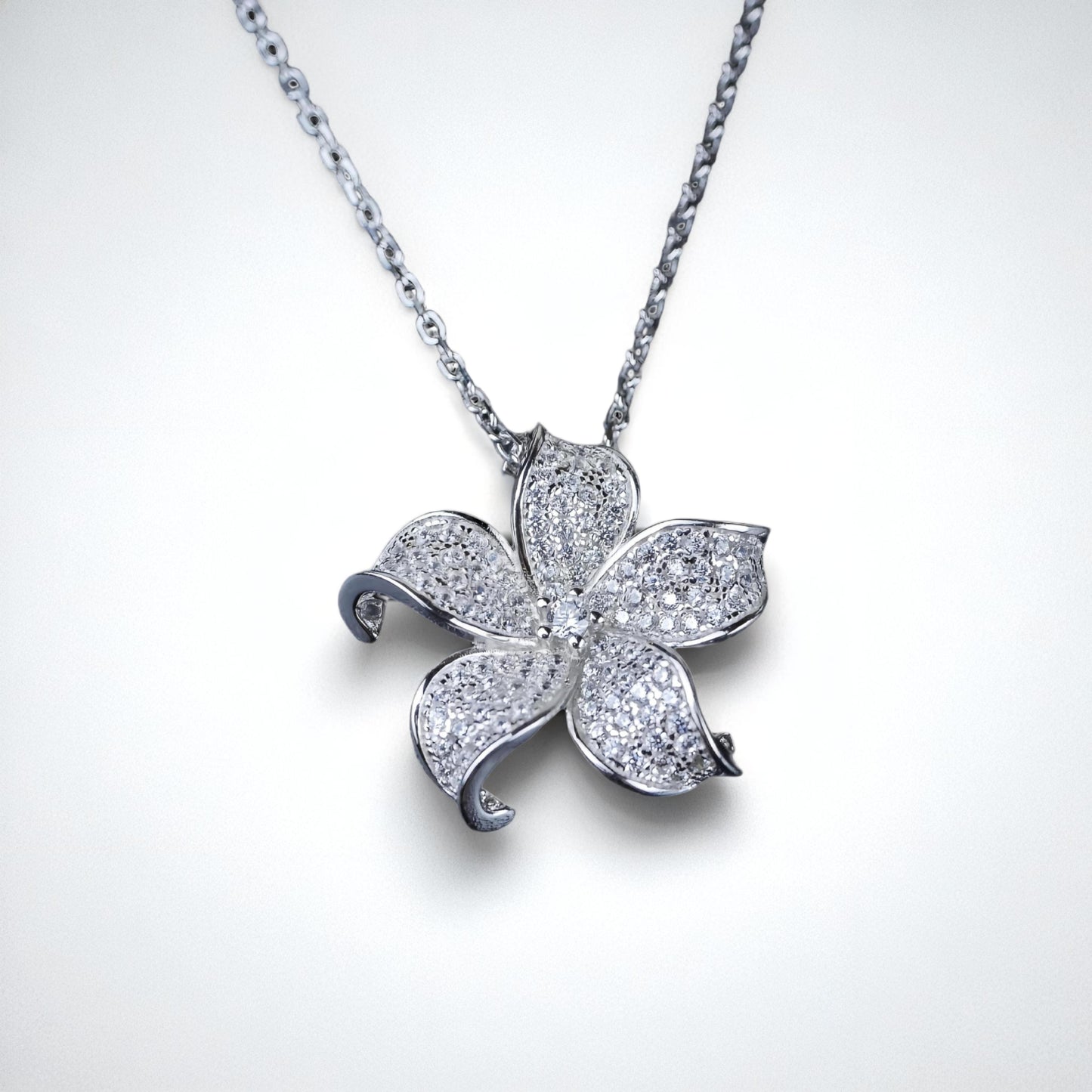 Silver flower-shaped pendant on a chain against a white background