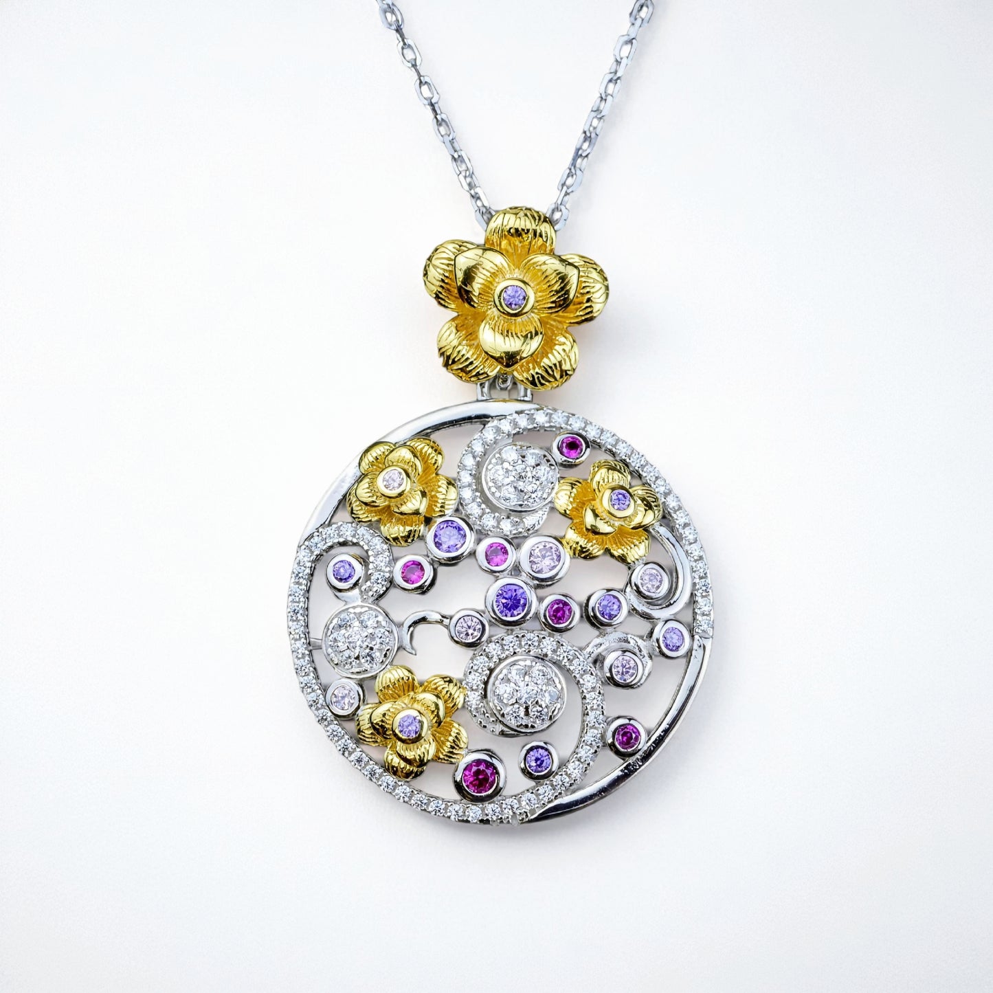 Jewelry pendant with floral designs and gemstones on a white background