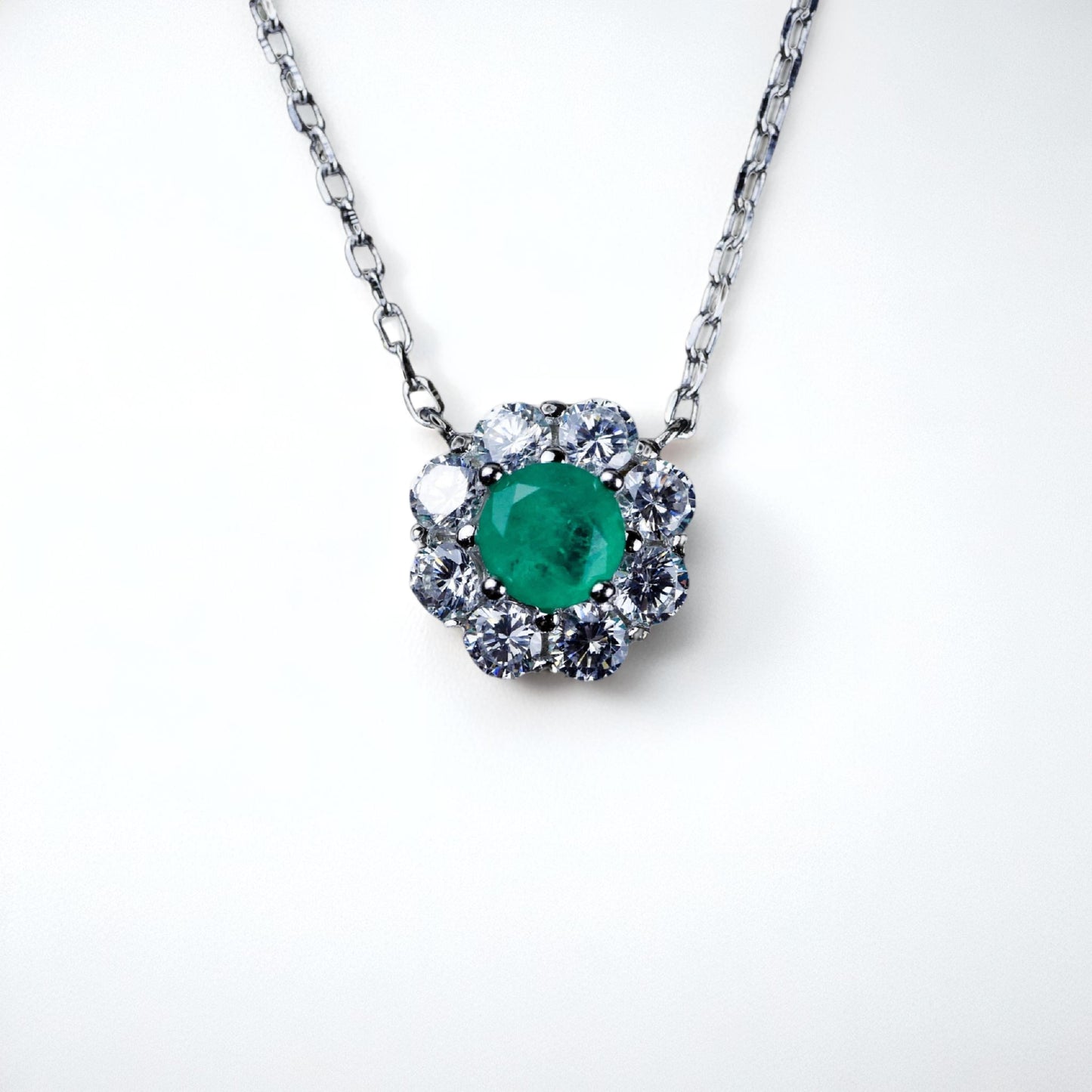 Necklace with a green gemstone and diamond-like stones on a white background
