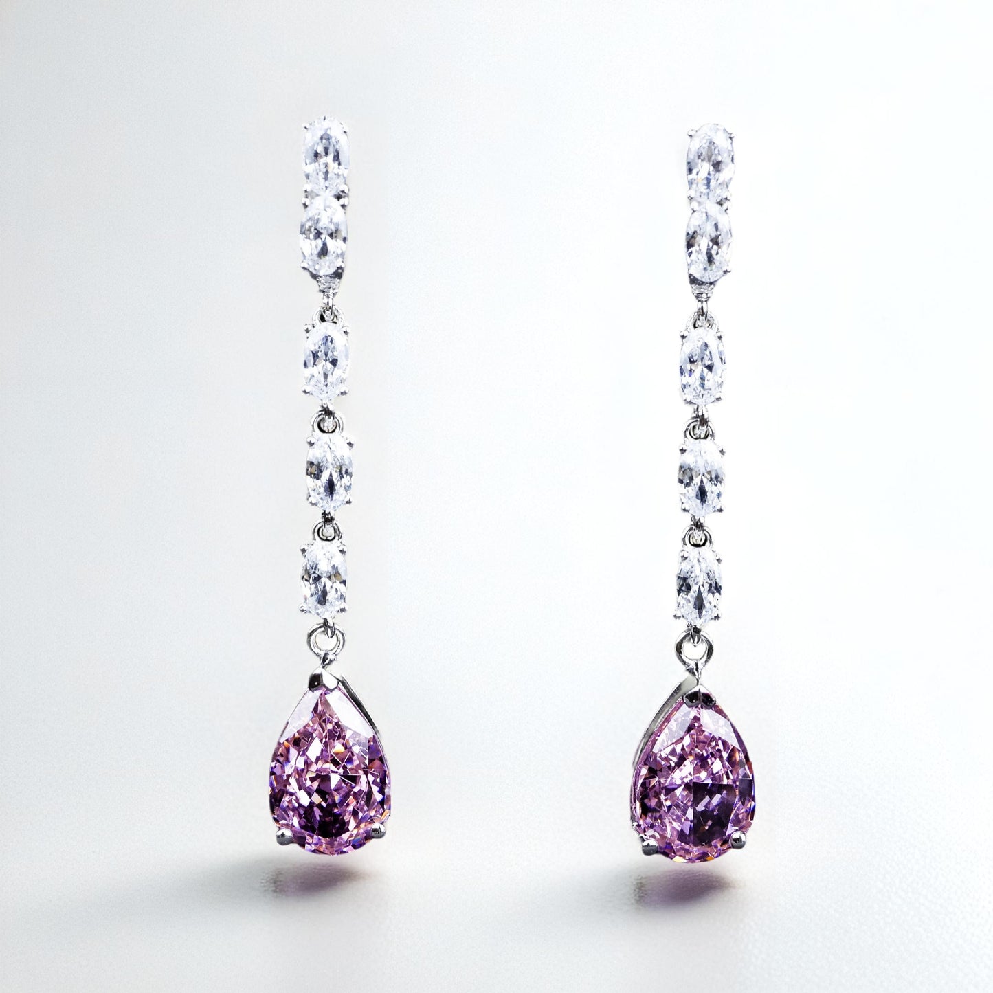Pair of earrings with pink teardrop gemstones on a white background