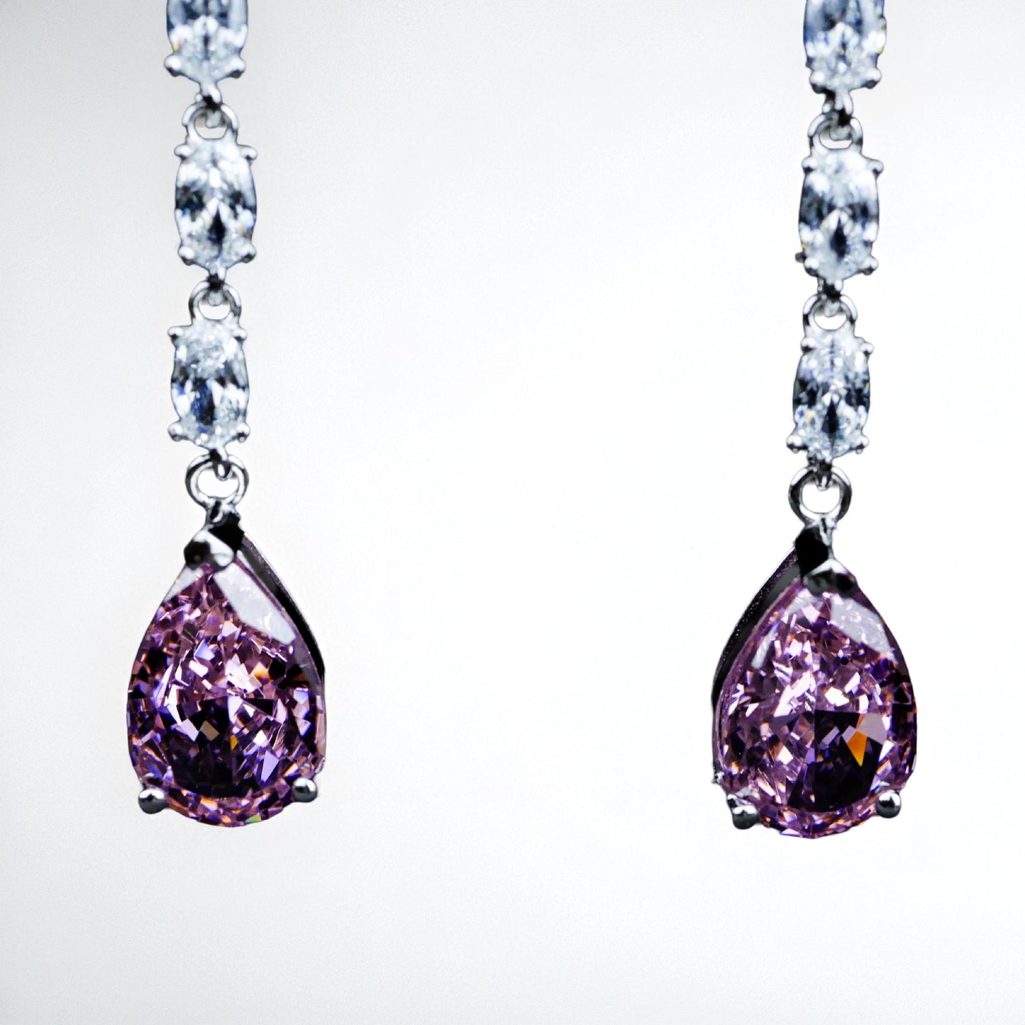 Pair of earrings with purple teardrop stones on a white background