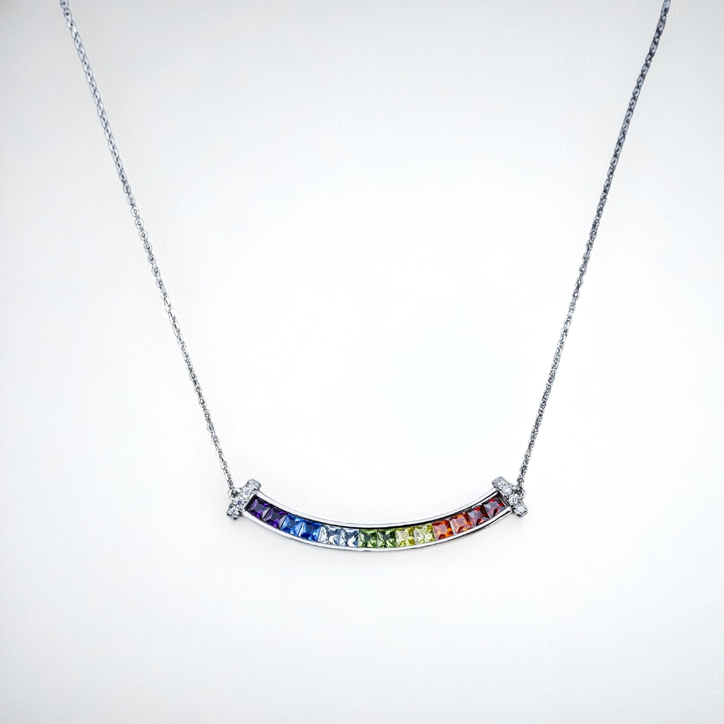 Necklace with a curved rainbow pendant on a white background