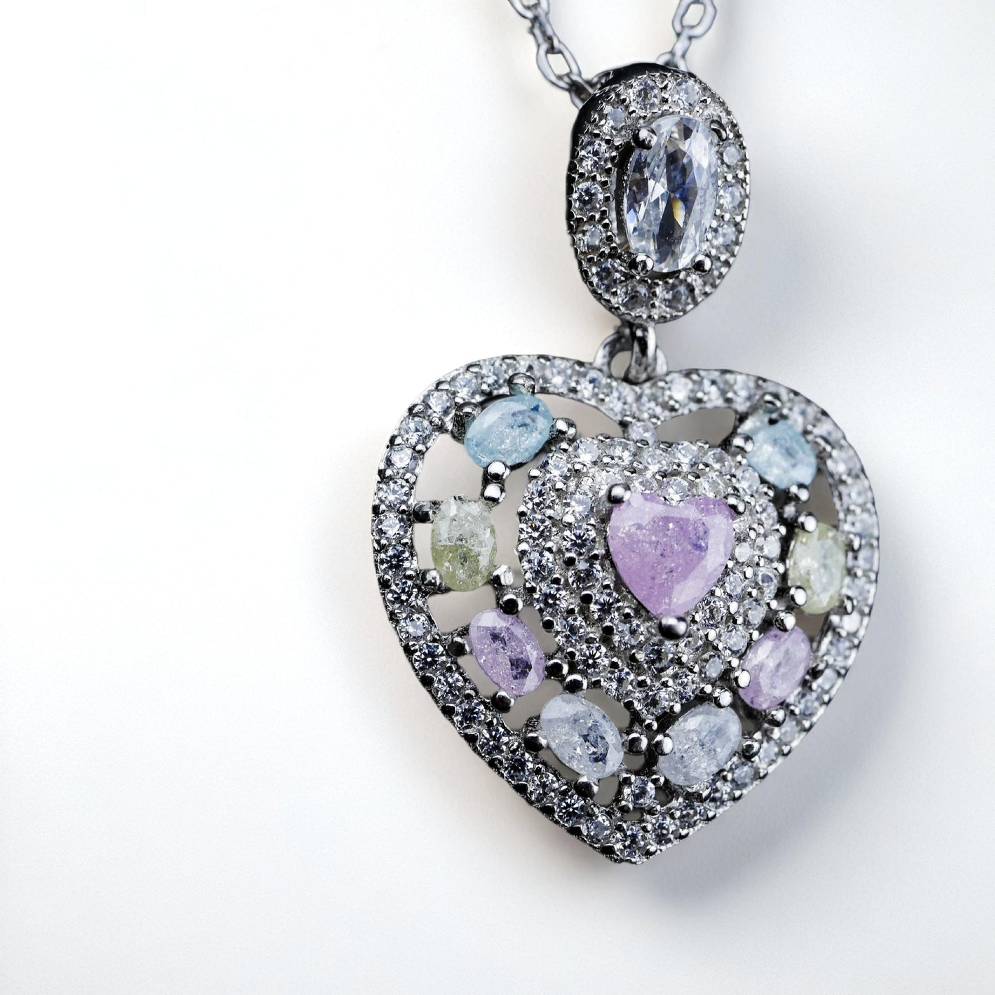 Heart-shaped pendant with multicolored gemstones on a white background