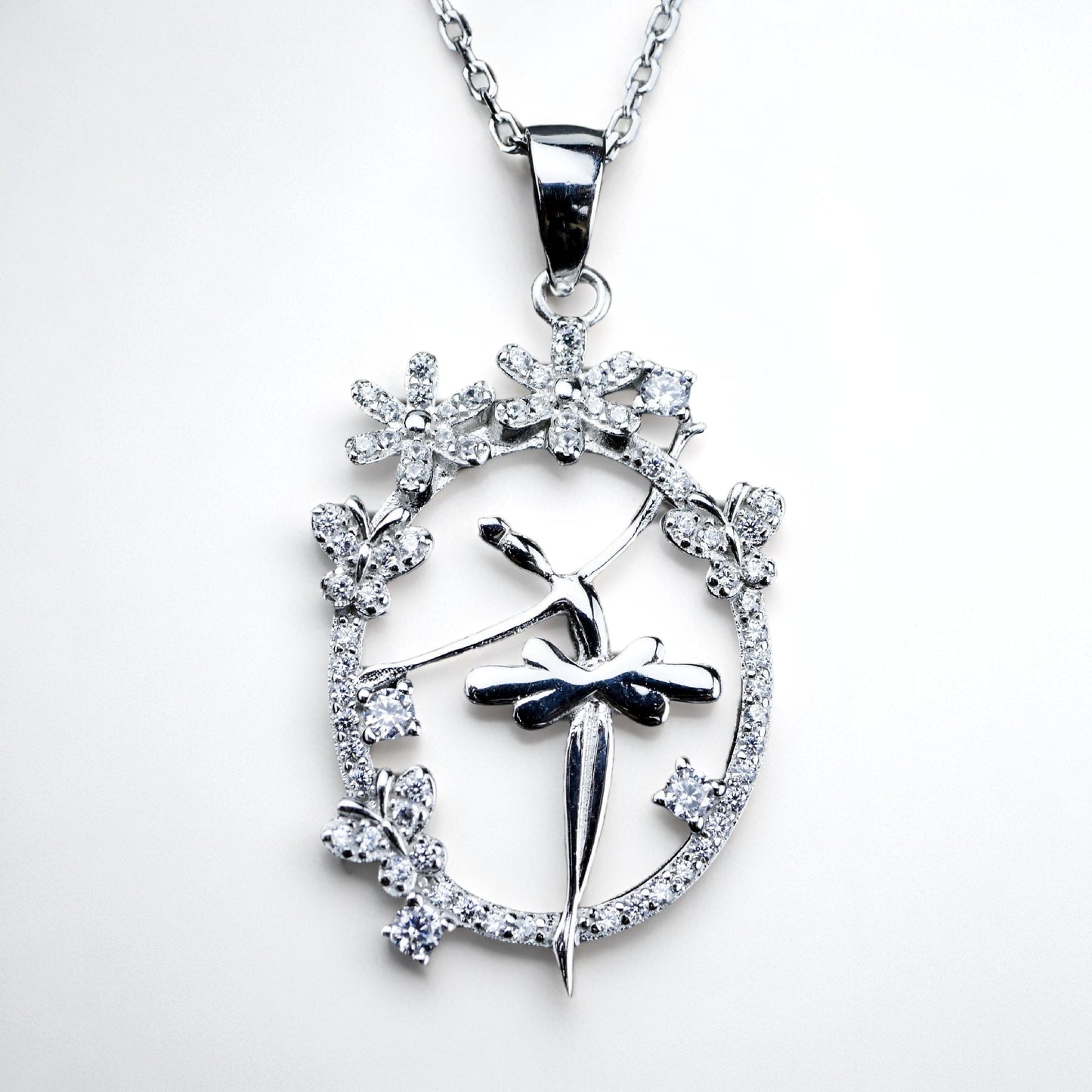 Silver pendant with floral design and central figure on a white background